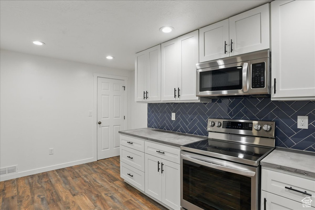 Kitchen with appliances with stainless steel finishes, baseboards, decorative backsplash, white cabinets, and recessed lighting