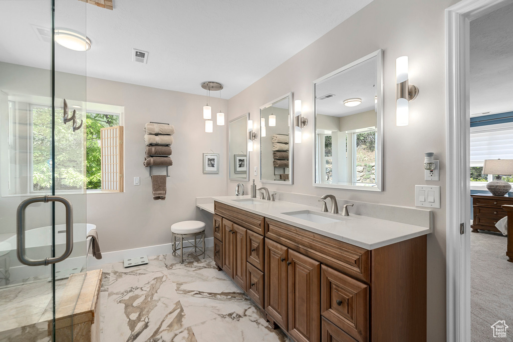Full bathroom featuring marble finish flooring, baseboards, double vanity, and a freestanding tub
