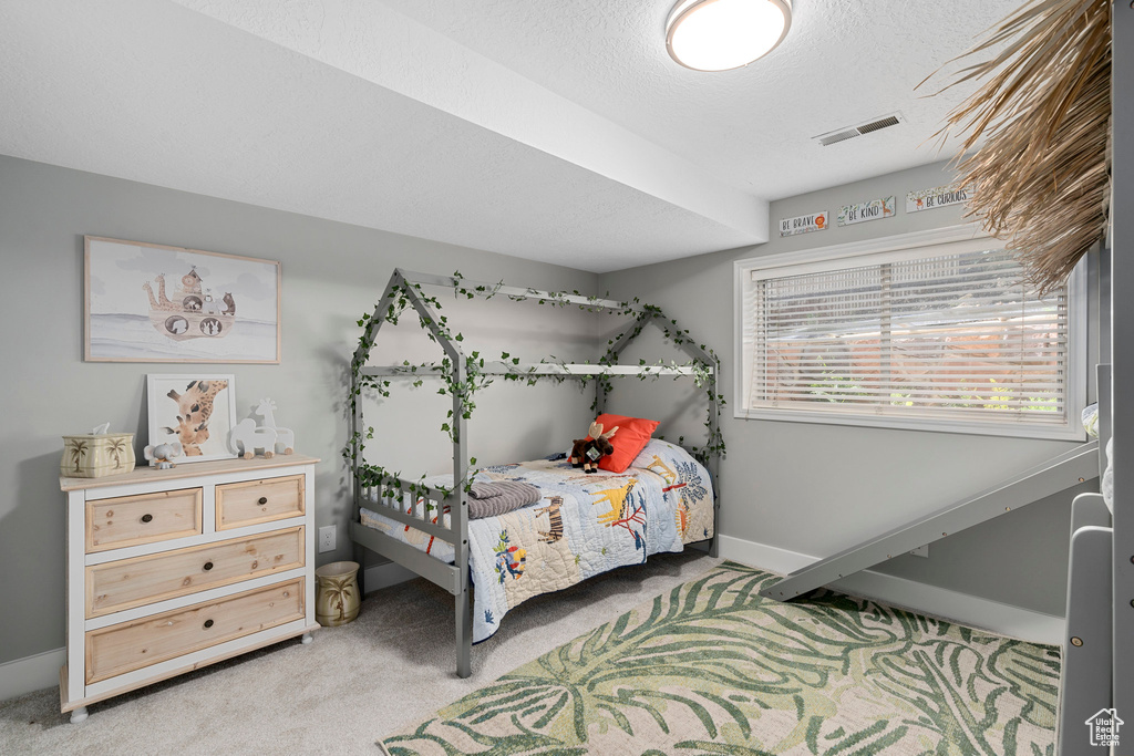 Bedroom featuring light carpet, baseboards, and a textured ceiling