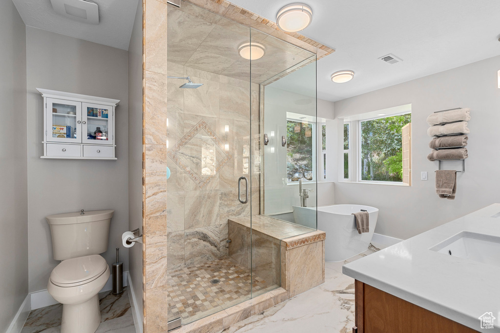 Full bathroom featuring marble finish floors, a stall shower, a freestanding tub, toilet, and baseboards