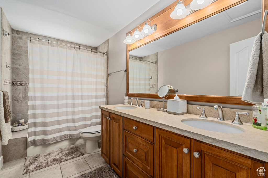 Full bathroom with tile patterned flooring, toilet, double vanity, and shower / bath combination with curtain