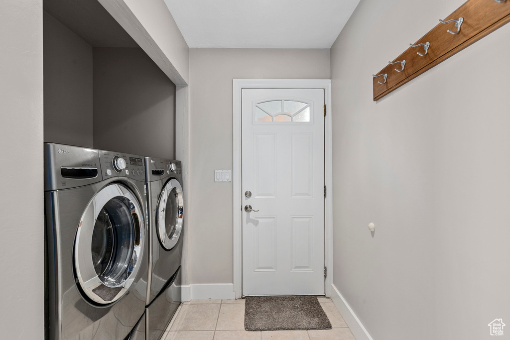 Laundry room with independent washer and dryer, light tile patterned floors, and baseboards