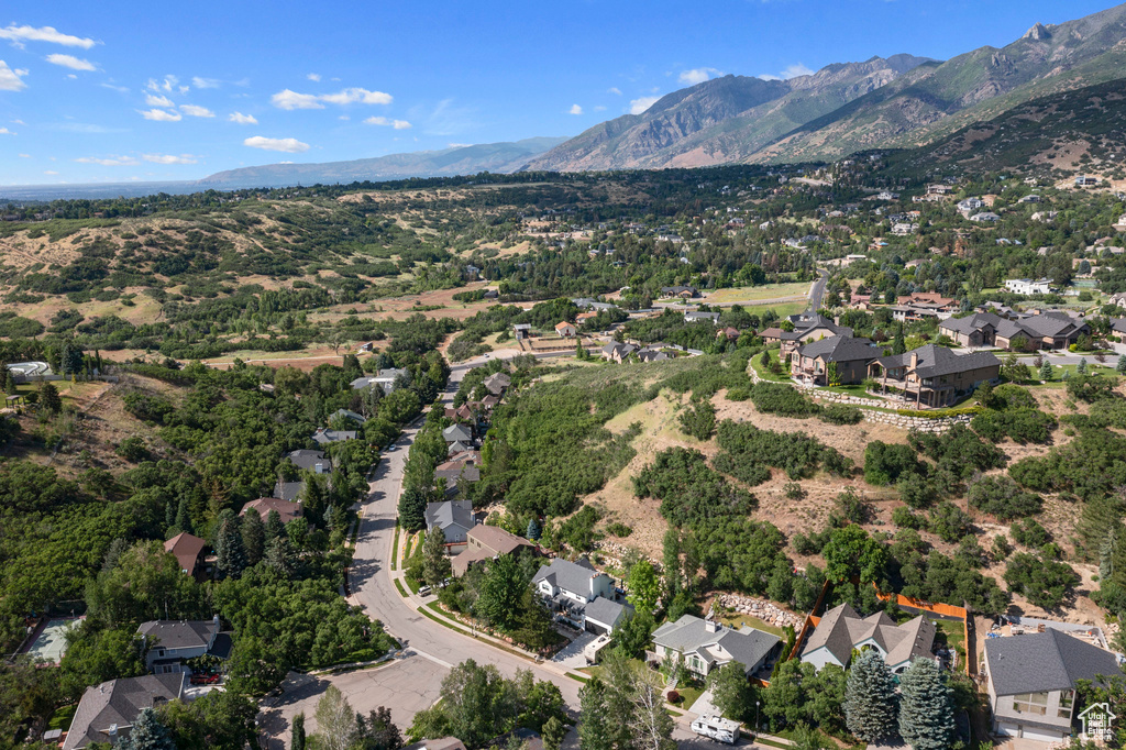 Aerial view of property and surrounding area featuring mountains and nearby suburban area
