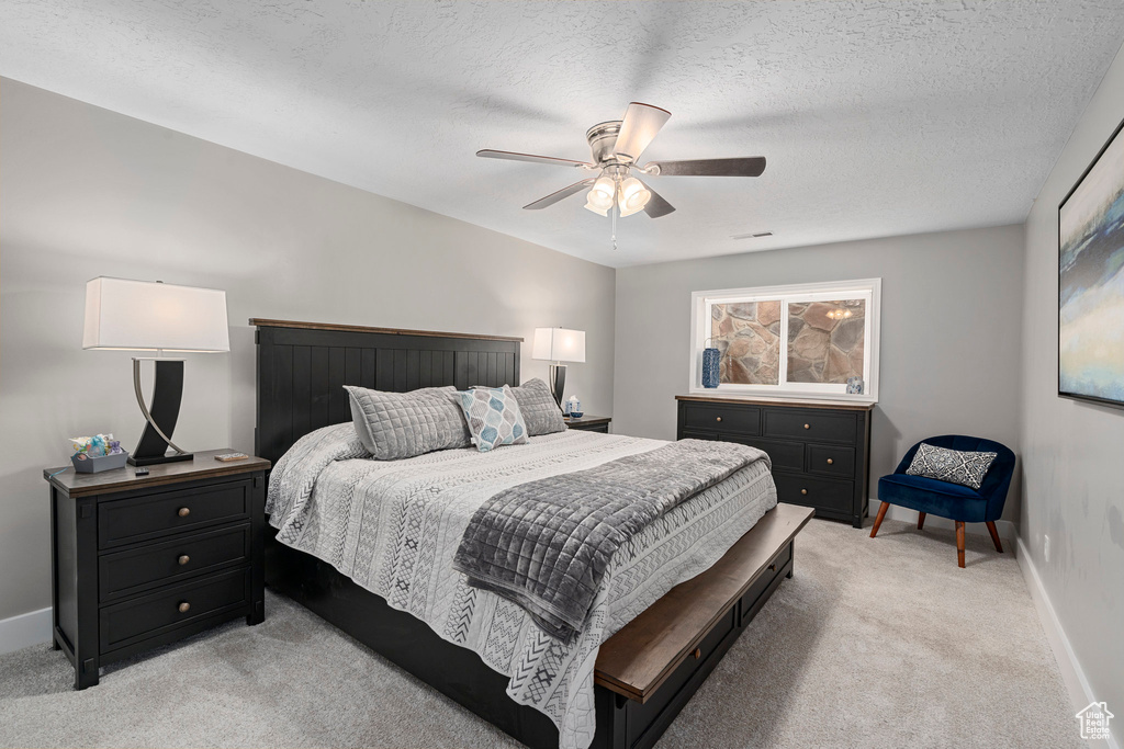 Bedroom featuring light carpet, baseboards, a ceiling fan, and a textured ceiling