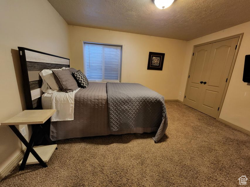 Carpeted bedroom featuring a textured ceiling and baseboards