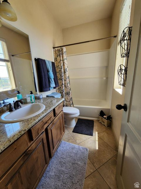 Bathroom with vanity, toilet, shower / tub combo, and tile patterned floors