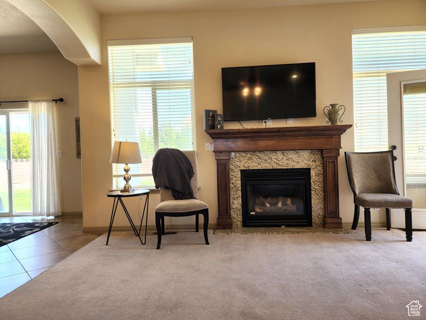 Living area with arched walkways, a fireplace, healthy amount of natural light, and tile patterned floors