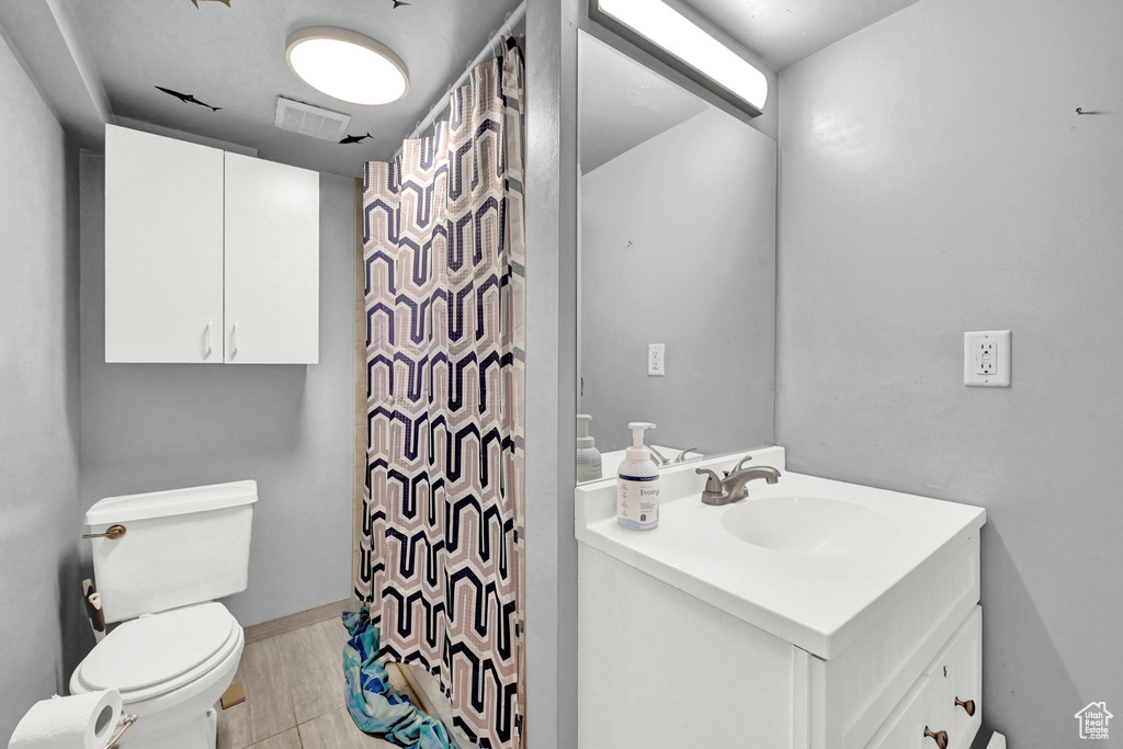 Bathroom with toilet, vanity, and a shower with shower curtain