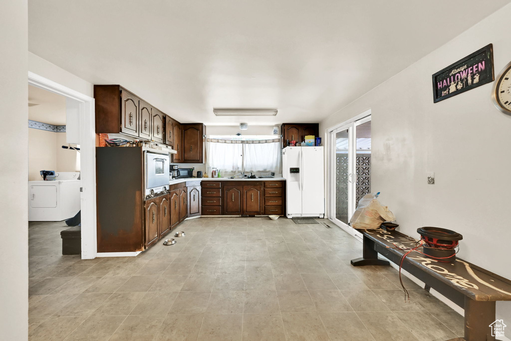 Kitchen with white appliances, washer / dryer, dark brown cabinets, and light countertops