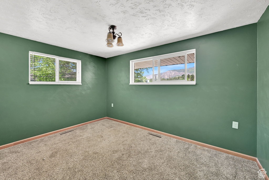 Carpeted empty room featuring baseboards and a textured ceiling