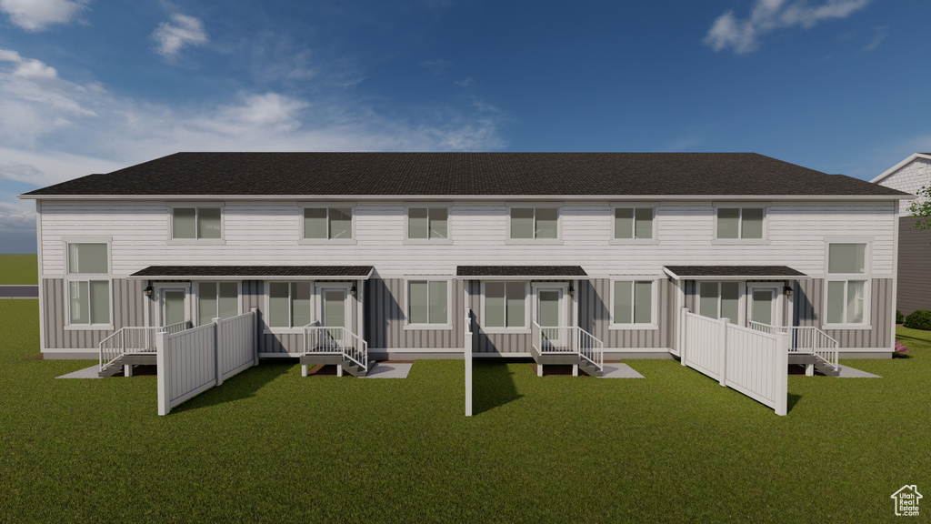 Rear view of house with a sunroom, a shingled roof, and a lawn