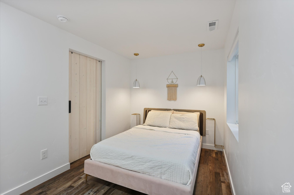 Bedroom with dark wood finished floors and baseboards