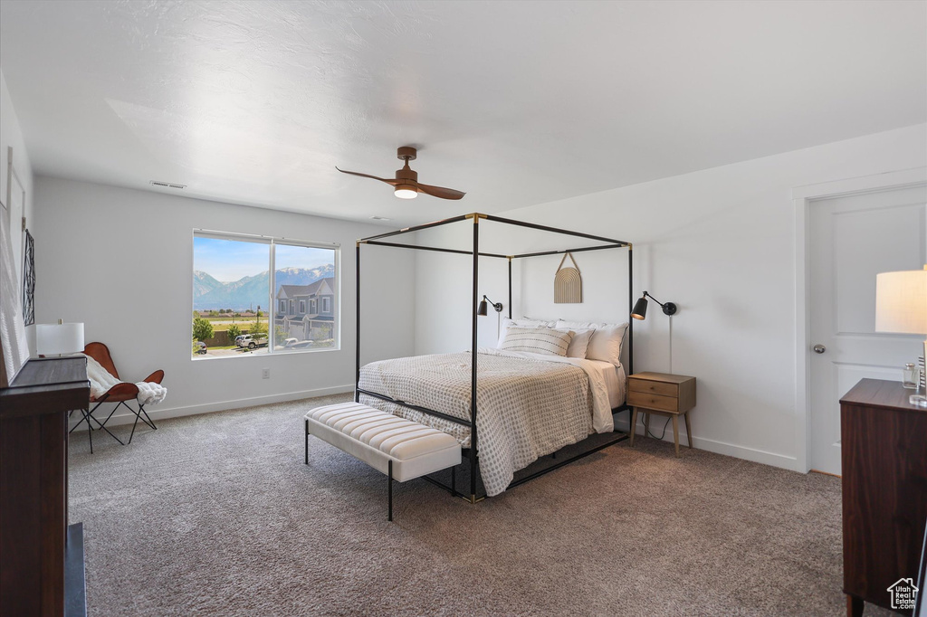 Carpeted bedroom with a ceiling fan, baseboards, and a mountain view
