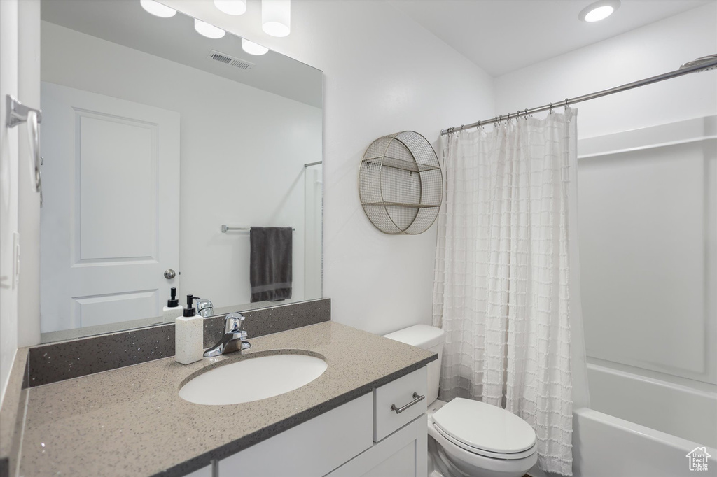 Bathroom with toilet, vanity, and shower / bath combo with shower curtain