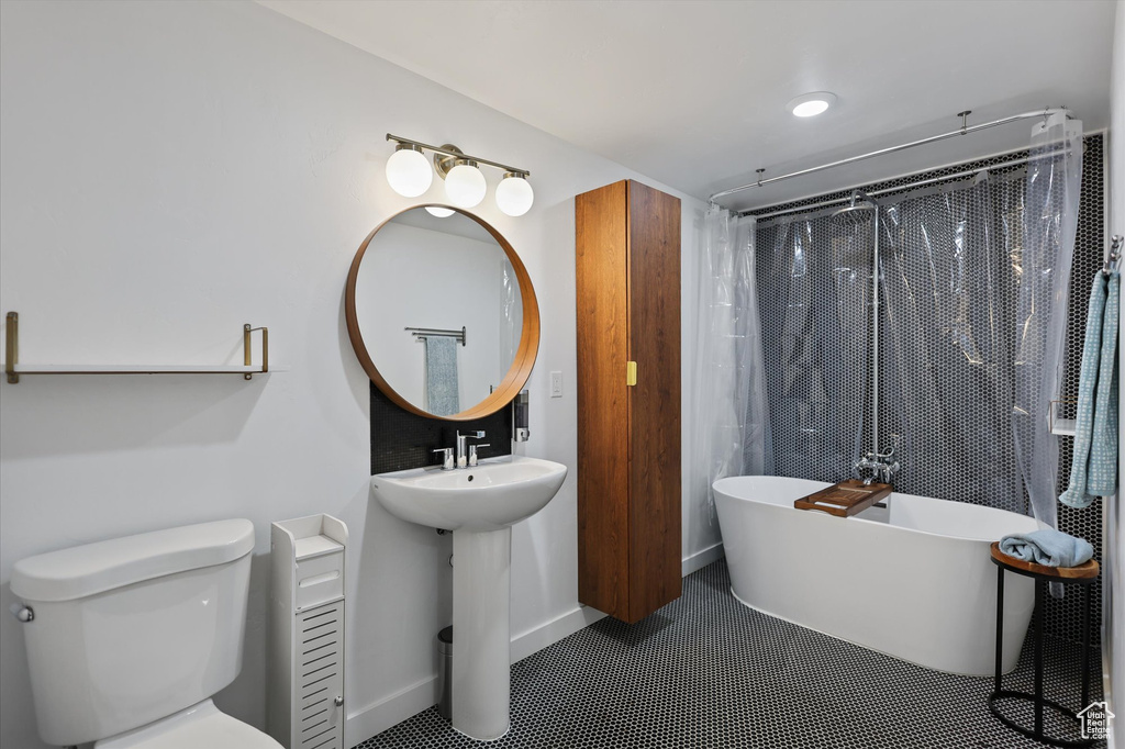 Bathroom featuring a freestanding bath, toilet, a sink, and a shower with curtain