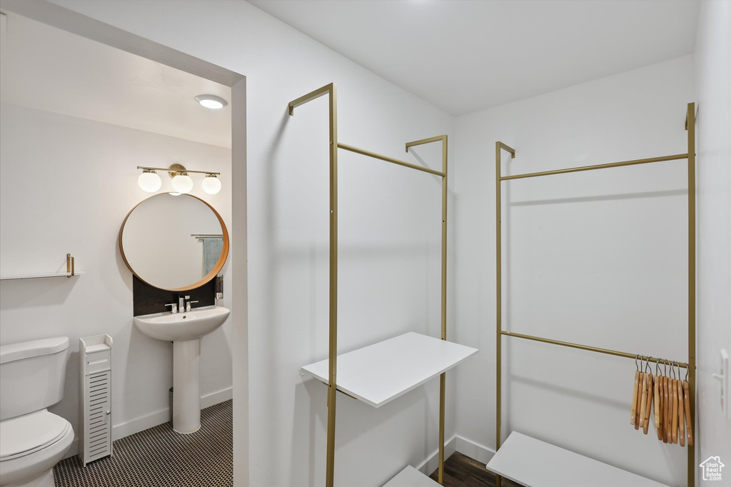 Bathroom with toilet, baseboards, a shower, a sink, and tile patterned flooring