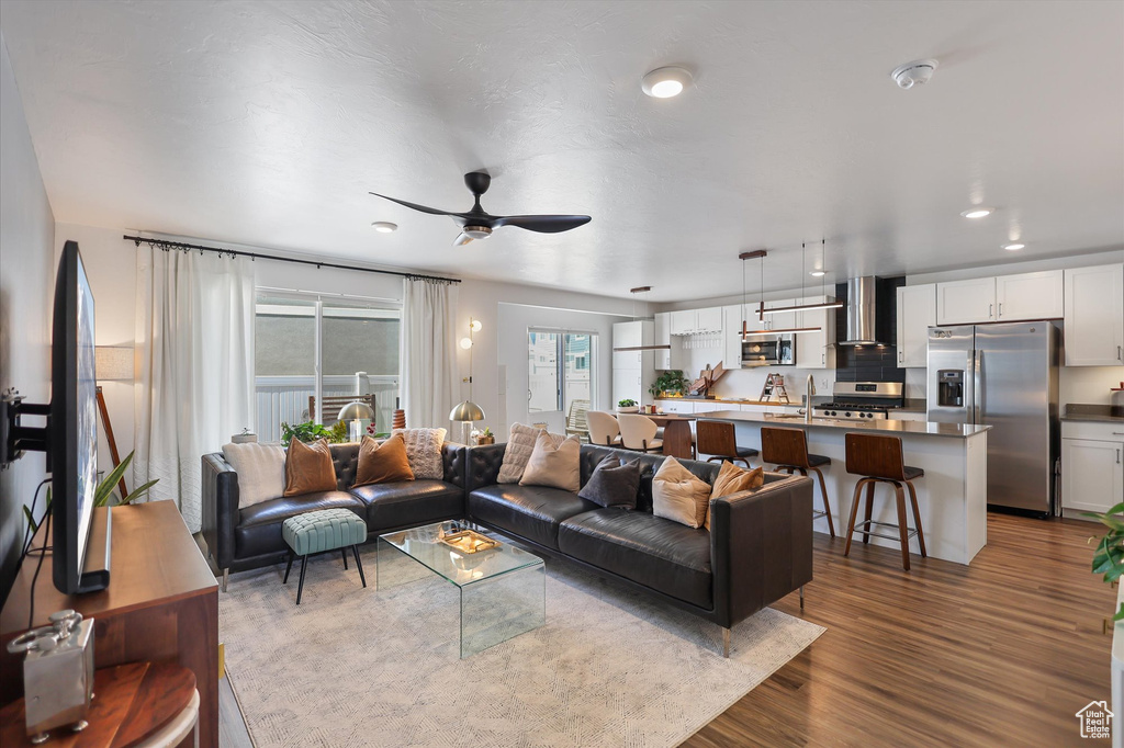 Living area featuring a ceiling fan and dark wood-type flooring