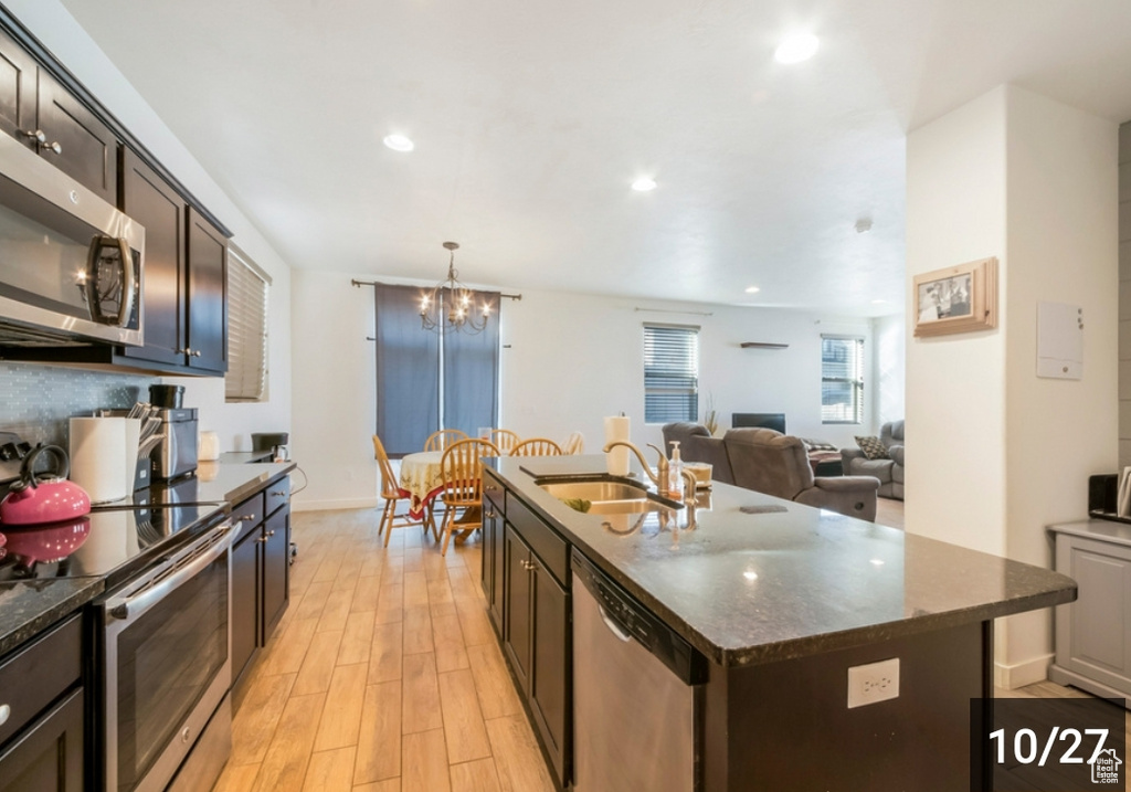 Kitchen with stainless steel appliances, a sink, light wood finished floors, dark brown cabinets, and a chandelier