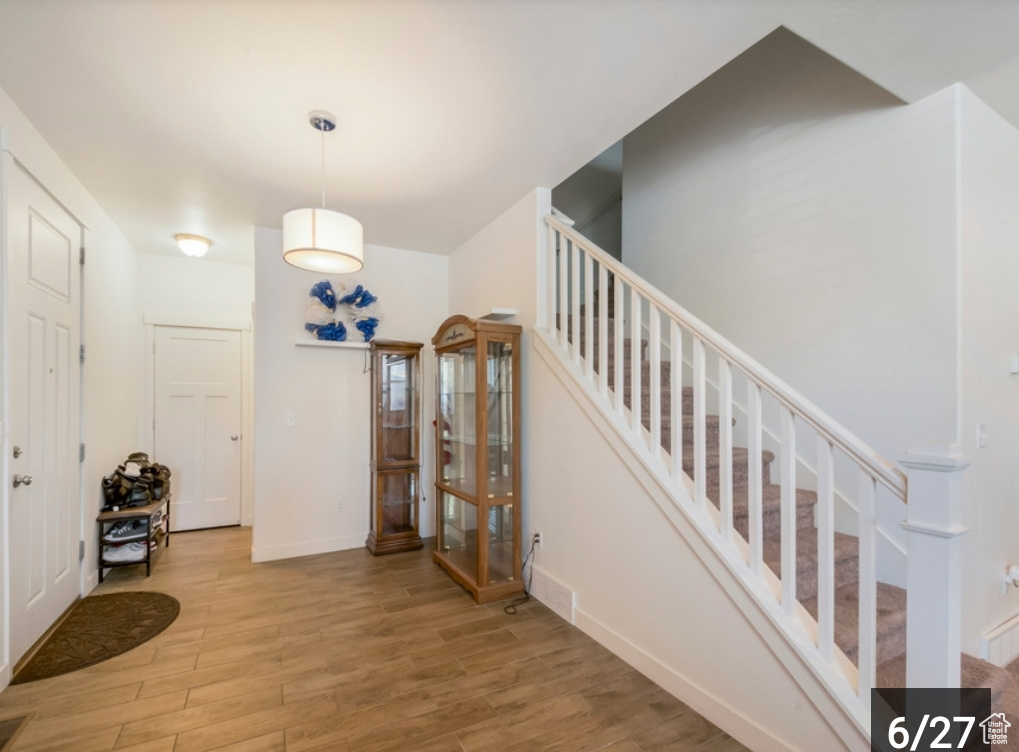 Foyer with wood finished floors, stairway, and baseboards