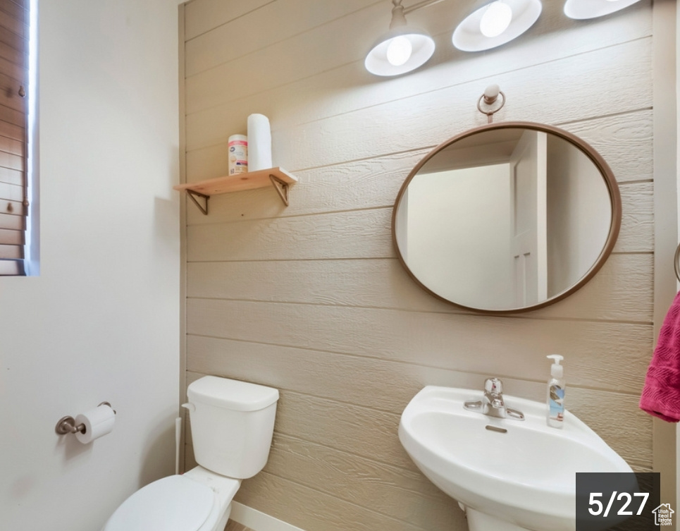Bathroom featuring a sink, toilet, and wood walls
