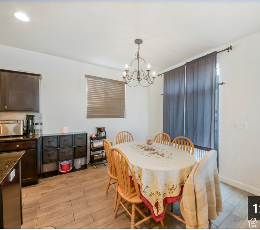 Dining space featuring light wood finished floors, a chandelier, and baseboards