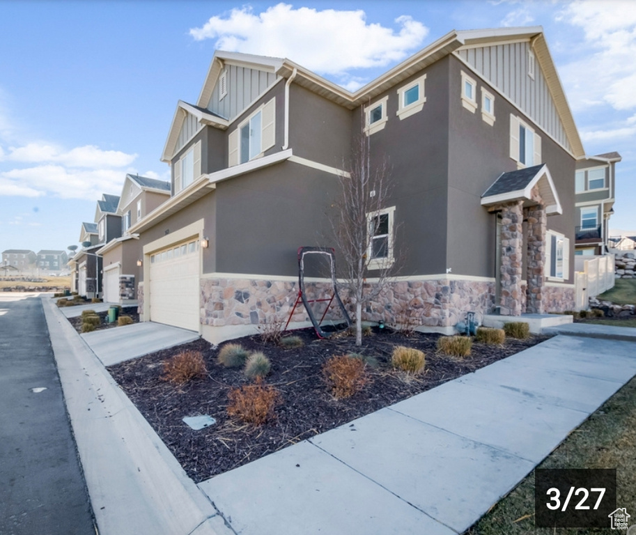 View of home's exterior featuring board and batten siding, stone siding, an attached garage, and stucco siding