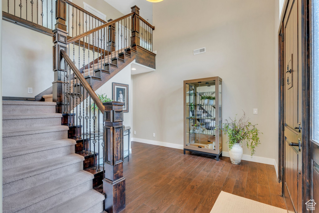Entrance foyer with a high ceiling, baseboards, wood finished floors, and stairs