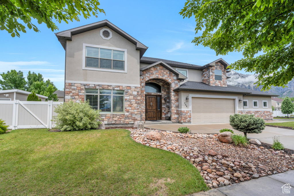 View of front of house featuring stucco siding, stone siding, a gate, and concrete driveway