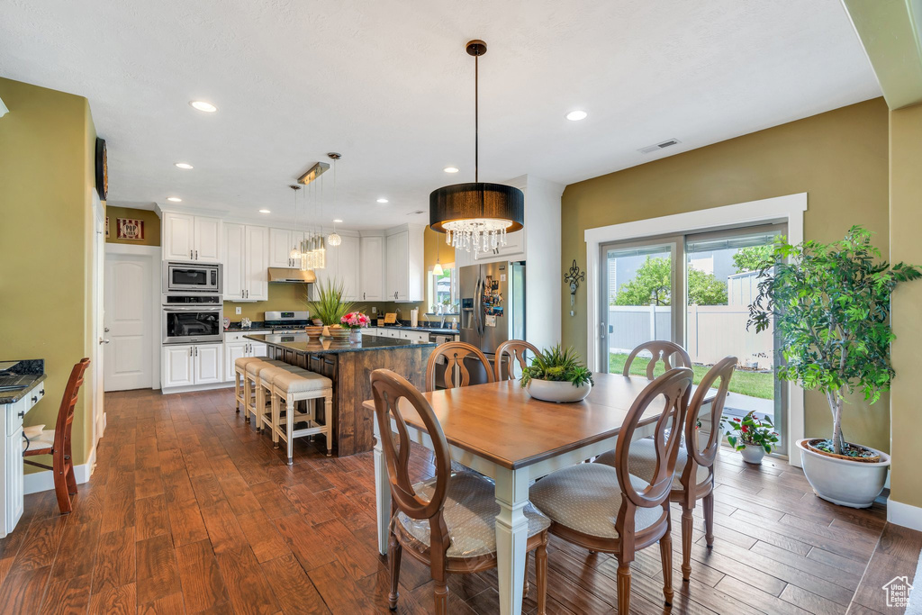 Dining area with dark wood finished floors, a chandelier, recessed lighting, and baseboards