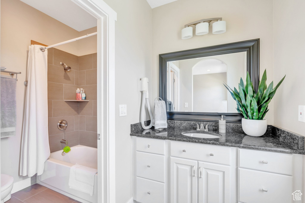 Bathroom featuring vanity, shower / bath combination with curtain, tile patterned floors, and toilet