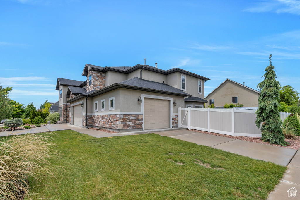 View of front facade with stone siding, stucco siding, an attached garage, and driveway