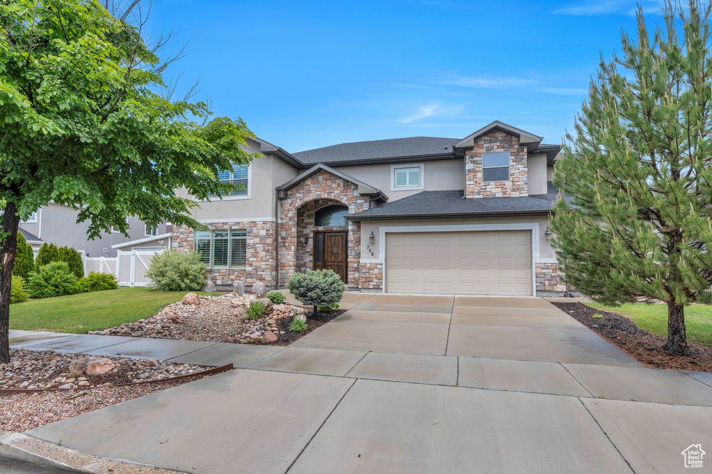 View of front of house featuring stucco siding, stone siding, concrete driveway, and a garage