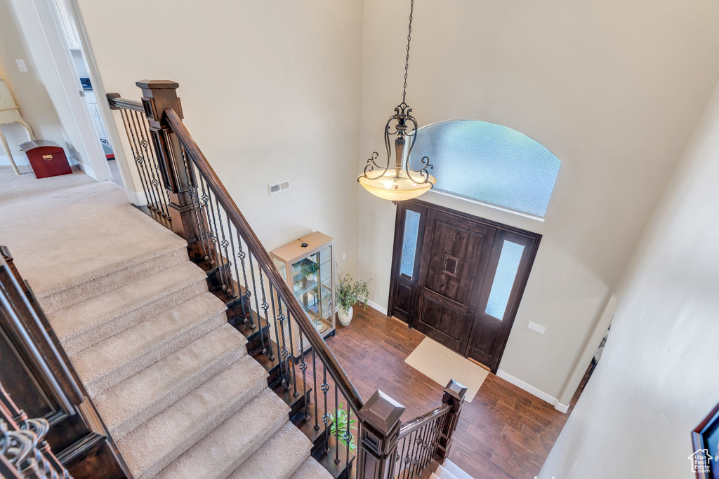 Entryway featuring a towering ceiling, baseboards, wood finished floors, and stairs