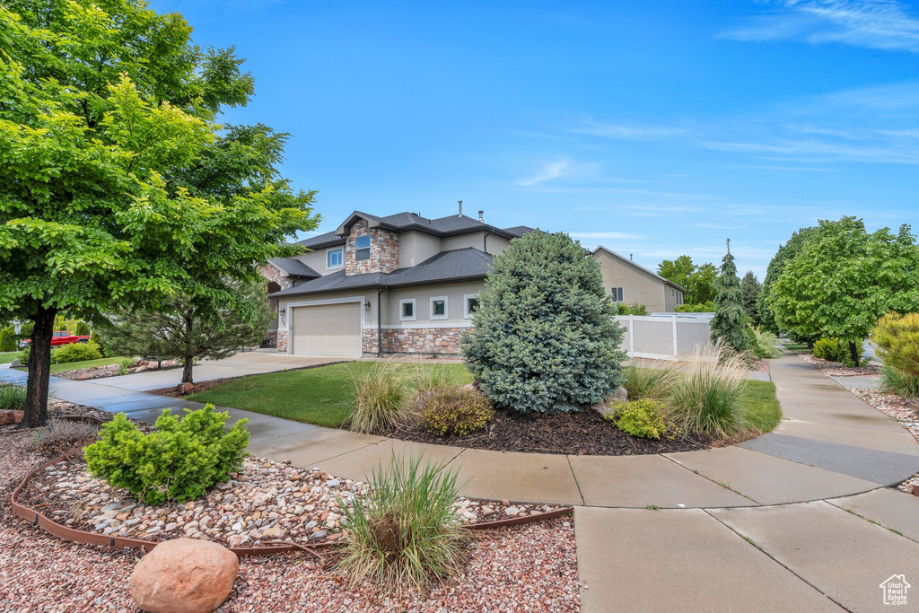 View of front of property featuring stone siding, driveway, a garage, and stucco siding