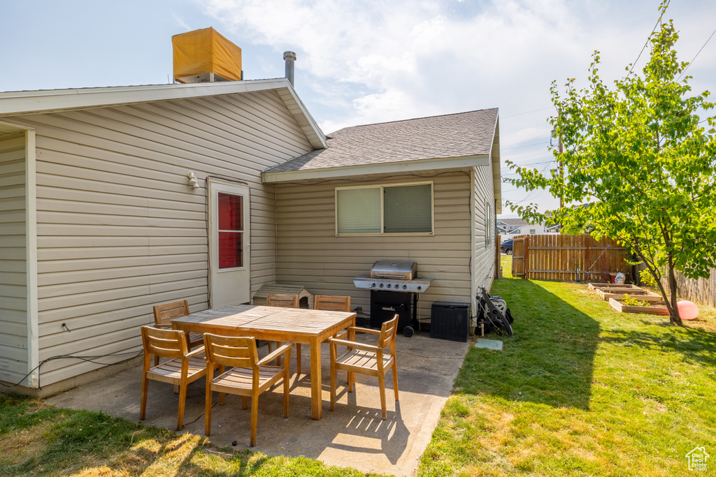 Back of property with a patio, outdoor dining space, a vegetable garden, and a shingled roof
