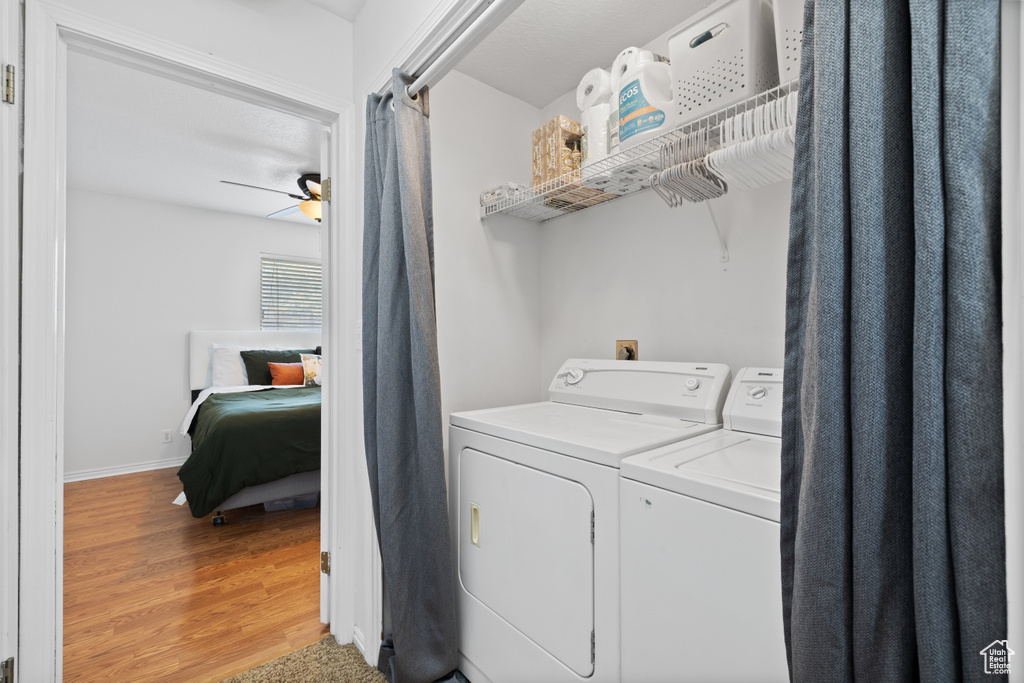 Laundry area featuring washer and clothes dryer, light wood-style floors, ceiling fan, and baseboards