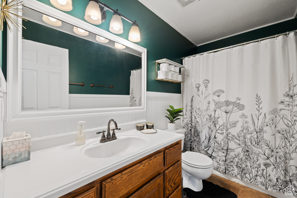 Bathroom featuring a wainscoted wall, toilet, vanity, and a shower with curtain