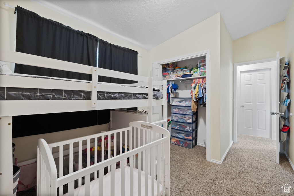 Carpeted bedroom featuring vaulted ceiling, a closet, baseboards, and a textured ceiling