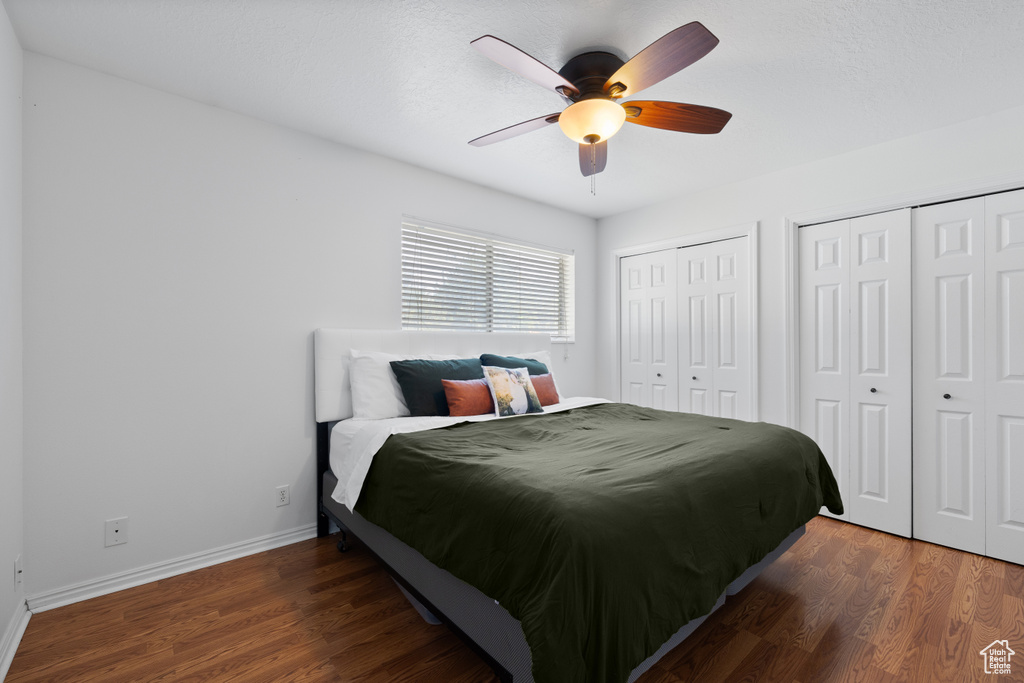 Bedroom featuring multiple closets, wood finished floors, baseboards, and ceiling fan