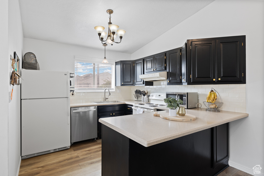 Kitchen with stainless steel appliances, a sink, under cabinet range hood, a peninsula, and lofted ceiling