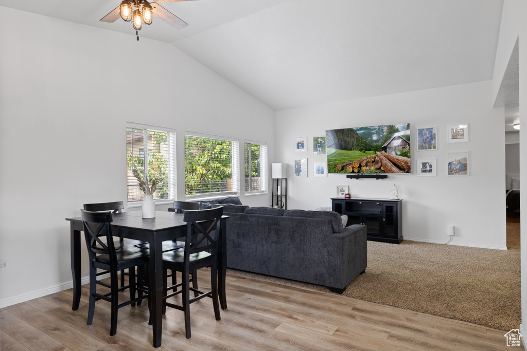 Dining space with a ceiling fan, light wood-style floors, baseboards, and high vaulted ceiling
