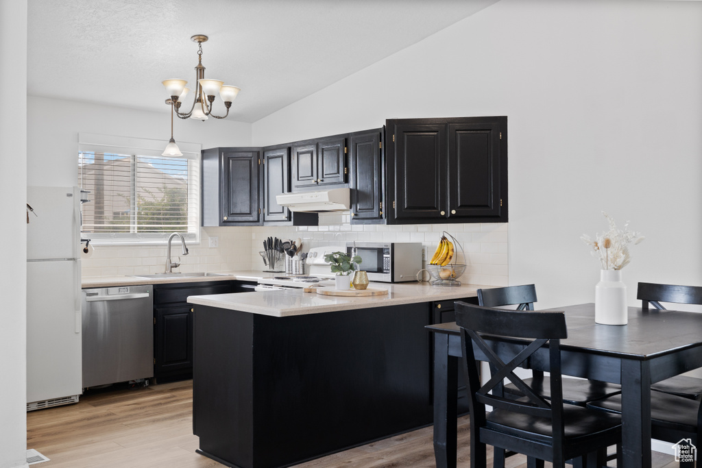 Kitchen with stainless steel appliances, a sink, lofted ceiling, light countertops, and a peninsula