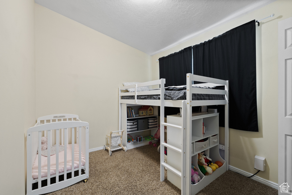 Bedroom featuring carpet flooring, baseboards, a textured ceiling, and vaulted ceiling