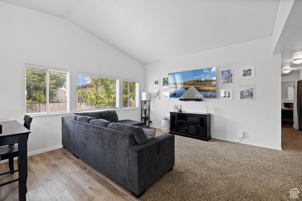 Living area featuring high vaulted ceiling, baseboards, and light wood-style floors