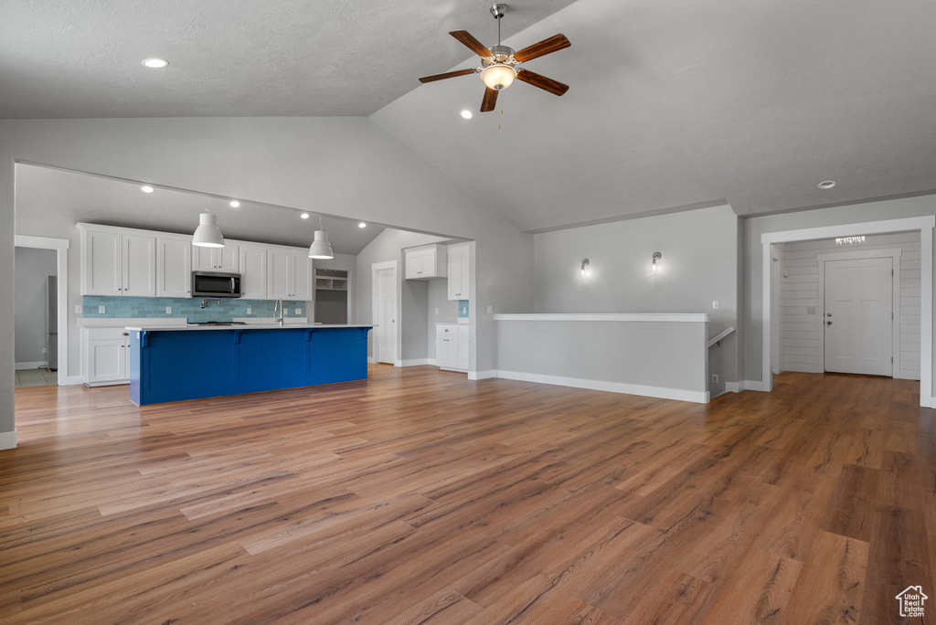 Unfurnished living room featuring ceiling fan, light wood-style flooring, recessed lighting, baseboards, and a sink