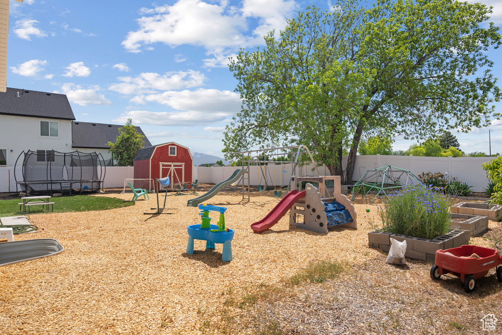 View of play area featuring a trampoline, a fenced backyard, and a vegetable garden