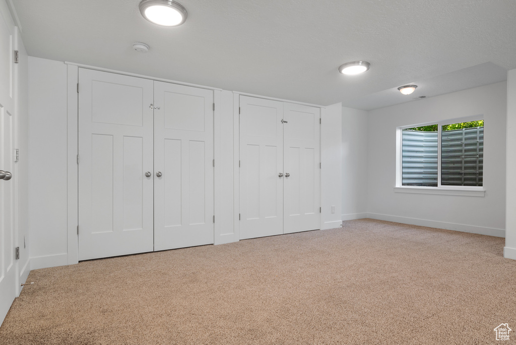 Unfurnished bedroom featuring two closets, carpet flooring, and baseboards