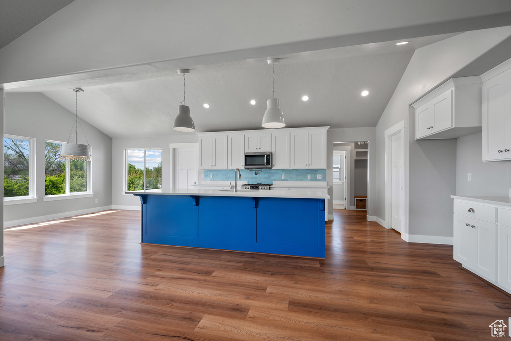 Kitchen with stainless steel microwave, light countertops, white cabinetry, baseboards, and recessed lighting