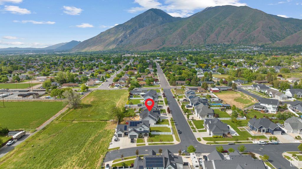 Aerial view of property and surrounding area featuring nearby suburban area and a mountain backdrop