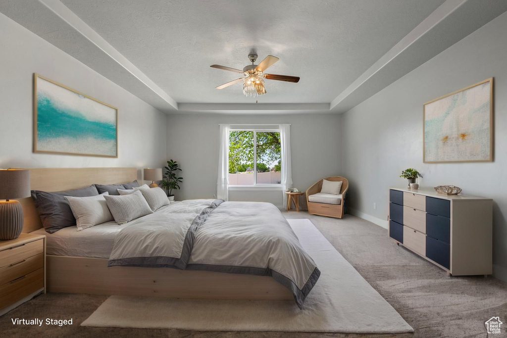 Bedroom with light carpet, a raised ceiling, baseboards, and a ceiling fan